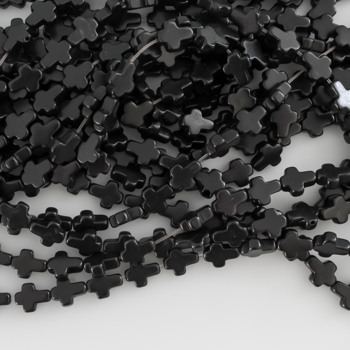 Black cross shaped beads that are a synthetic turquoise material dyed black Sold by the strand. Each strand is 16 inches long with about 38pcs/strand.