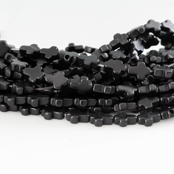 Black cross shaped beads that are a synthetic turquoise material dyed black Sold by the strand. Each strand is 16 inches long with about 38pcs/strand.