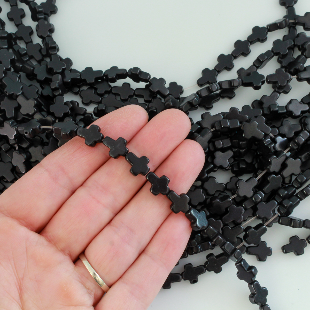 Black cross shaped beads that are a synthetic turquoise material dyed black Sold by the strand. Each strand is 16 inches long with about 38pcs/strand.