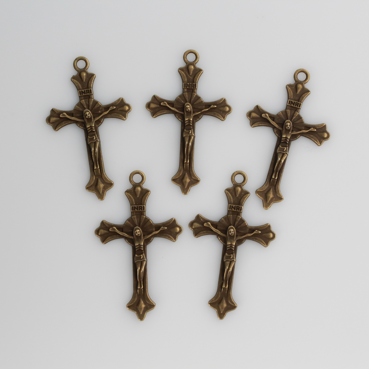 Small crucifix cross in an antiqued bronze color with a starburst design behind Jesus and ornate flared ends