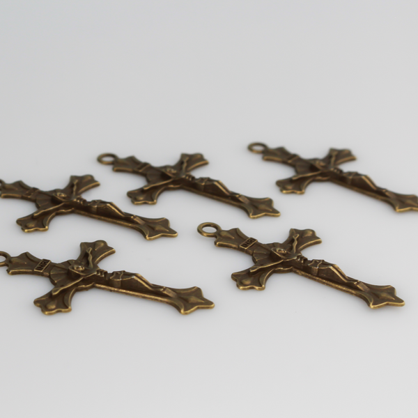 Small crucifix cross in an antiqued bronze color with a starburst design behind Jesus and ornate flared ends