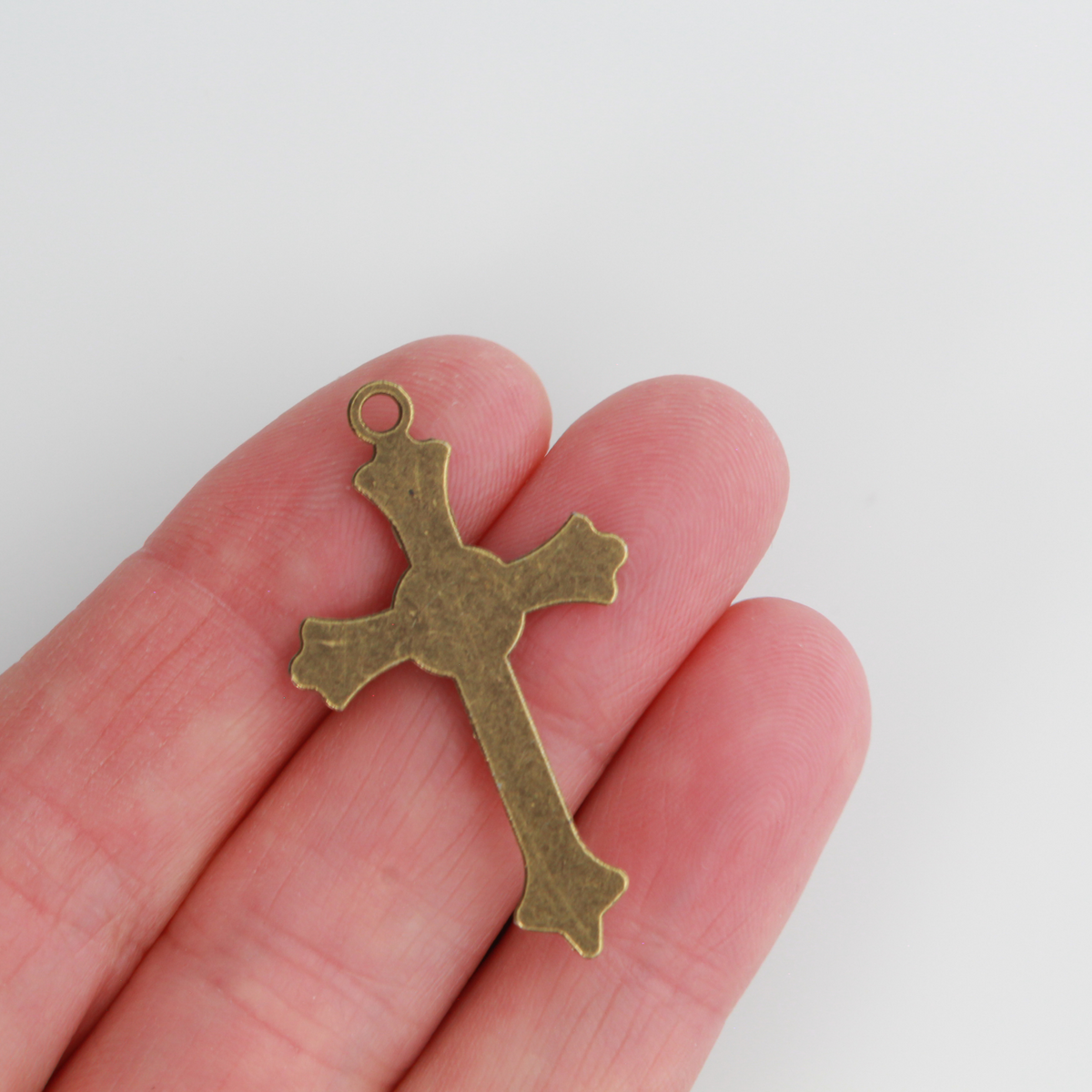 Small crucifix cross in an antiqued bronze color with a starburst design behind Jesus and ornate flared ends