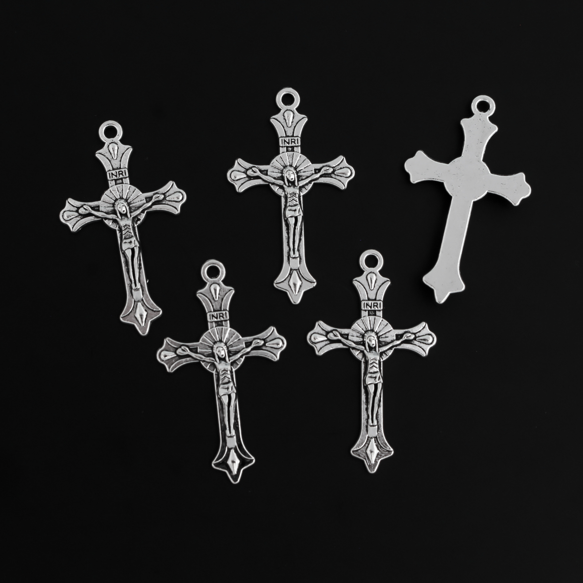 Small crucifix cross in an antiqued silver color with a starburst design behind Jesus and ornate flared ends.