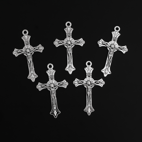 Small crucifix cross in an antiqued silver color with a starburst design behind Jesus and ornate flared ends.