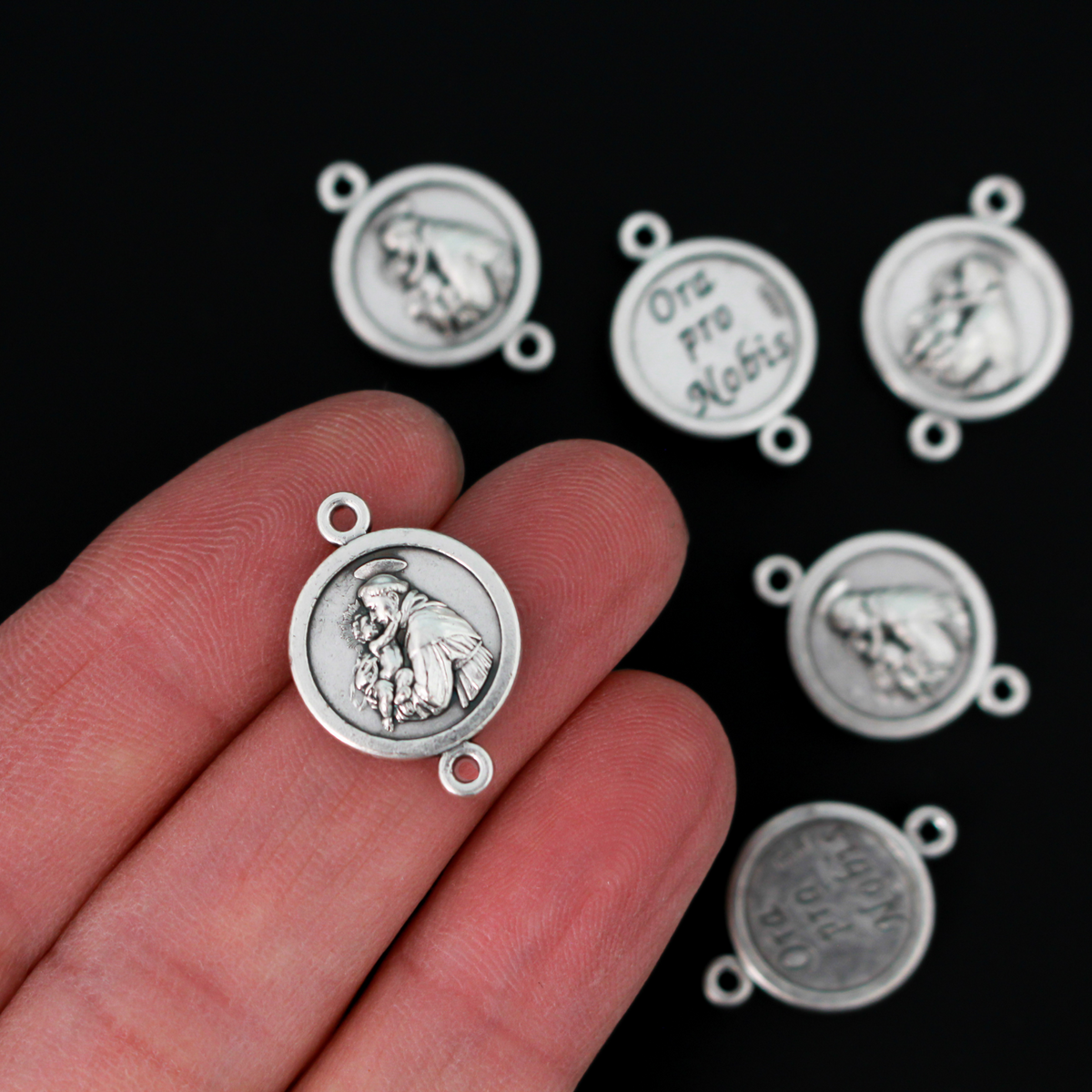 Saint Anthony round flat connector links that are silver oxidized plating on a base metal. The backside is marked "Ora Pro Nobis" in Latin which translates to pray for us.