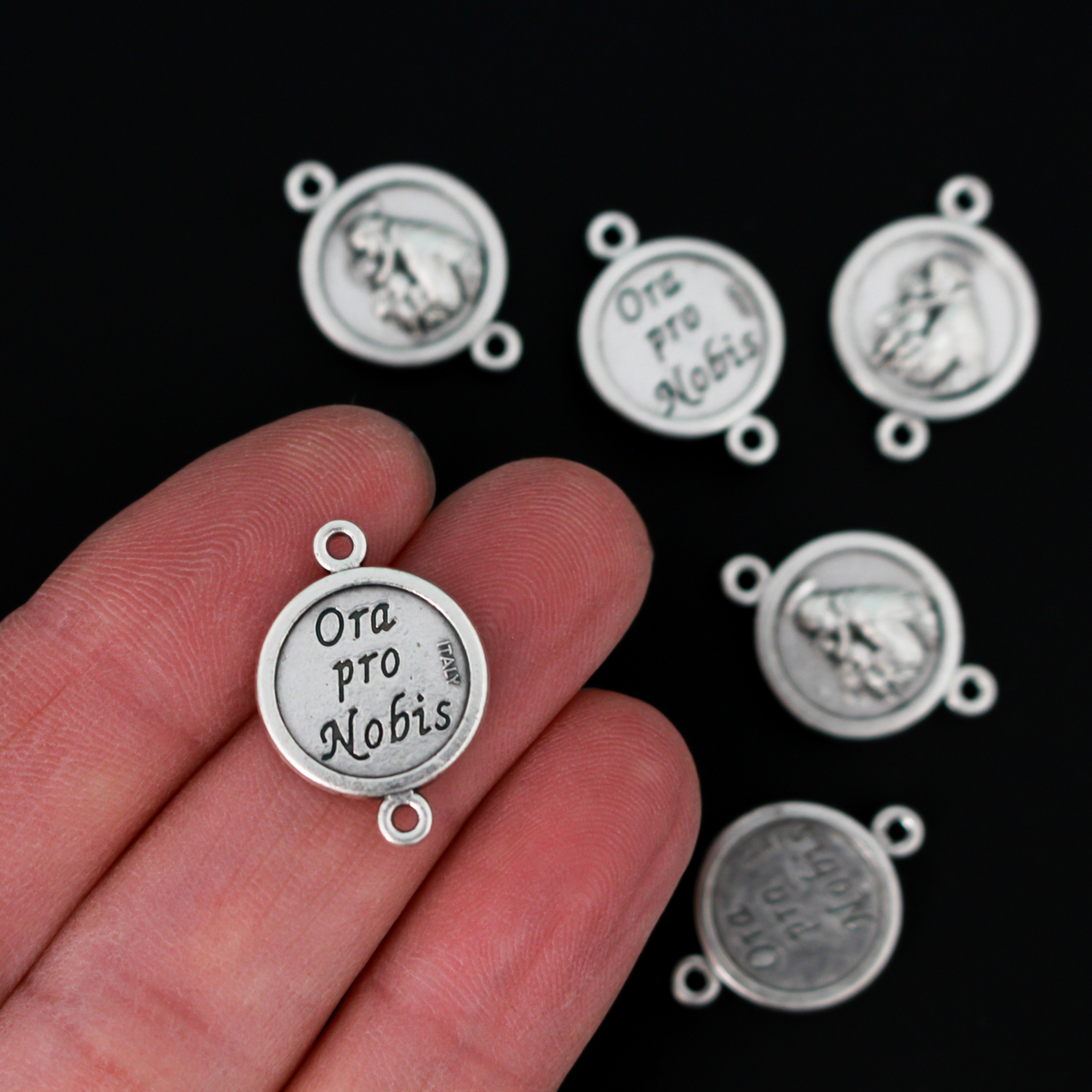 Saint Anthony round flat connector links that are silver oxidized plating on a base metal. The backside is marked "Ora Pro Nobis" in Latin which translates to pray for us.