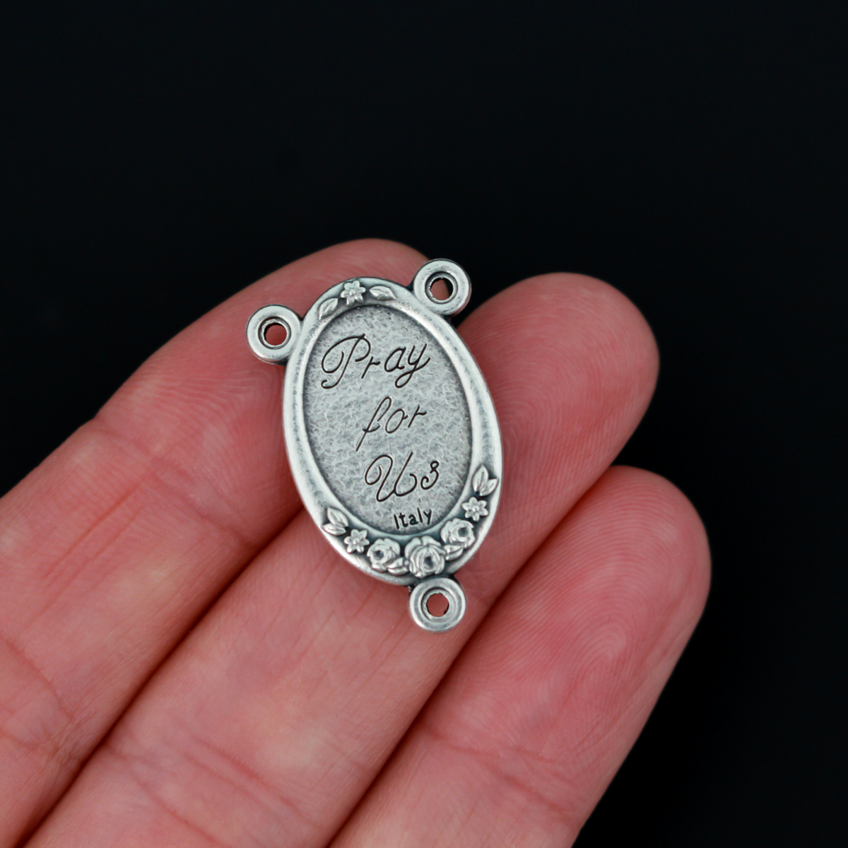 Rosary center that has a color image of Saint Therese of Lisieux inlaid in a silver oxidized Center with a flower detail on the edge