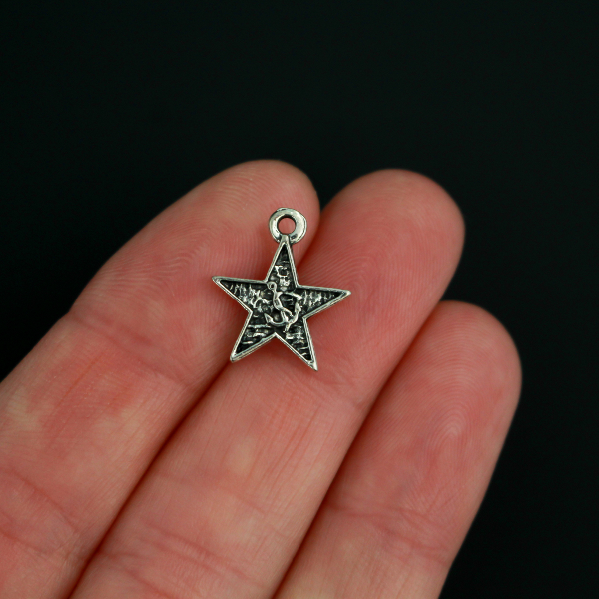 Small star-shaped charms that feature The Blessed Virgin Mary as Our Lady of the Sea on the front side and an anchor on the backside.