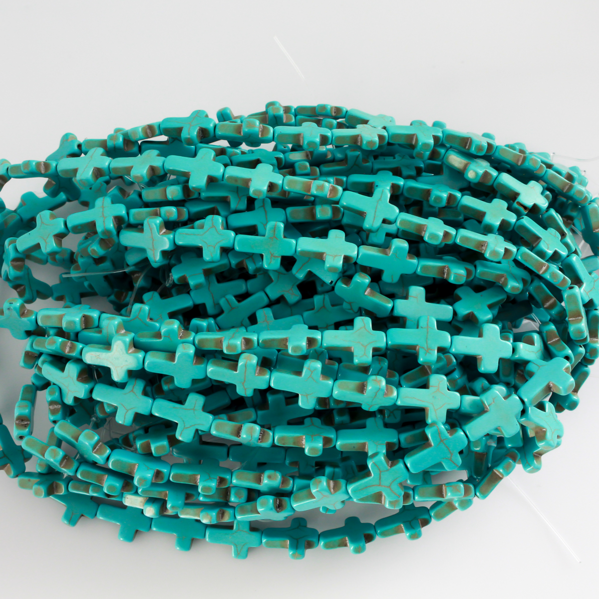 Cross shaped beads that are a synthetic turquoise material called howlite, each cross is 16x12mm