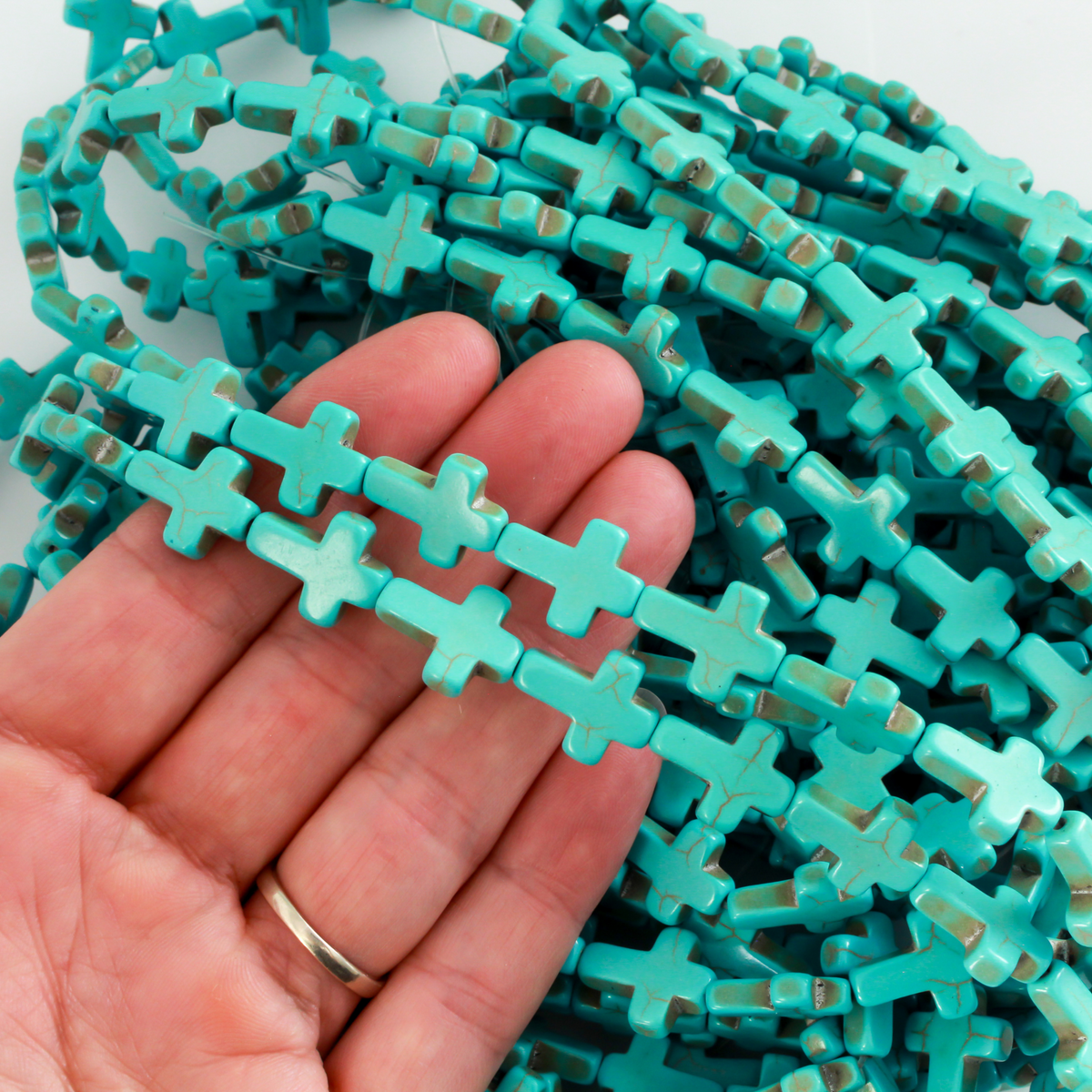 Cross shaped beads that are a synthetic turquoise material called howlite, each cross is 16x12mm