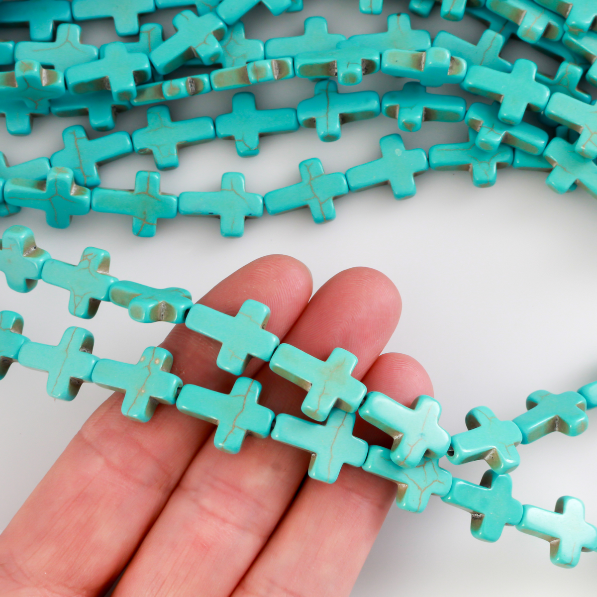 Cross shaped beads that are a synthetic turquoise material called howlite, each cross is 16x12mm