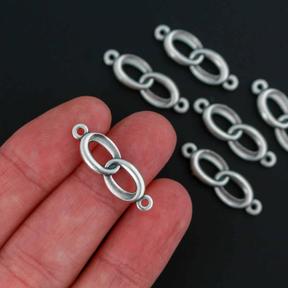Connector links that are intertwined wedding rings in an antique silver color.