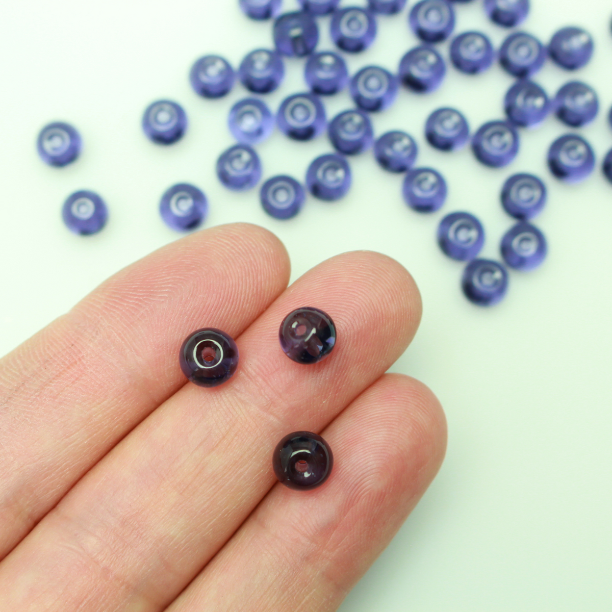 6mm round glass beads that are a transparent purple color.