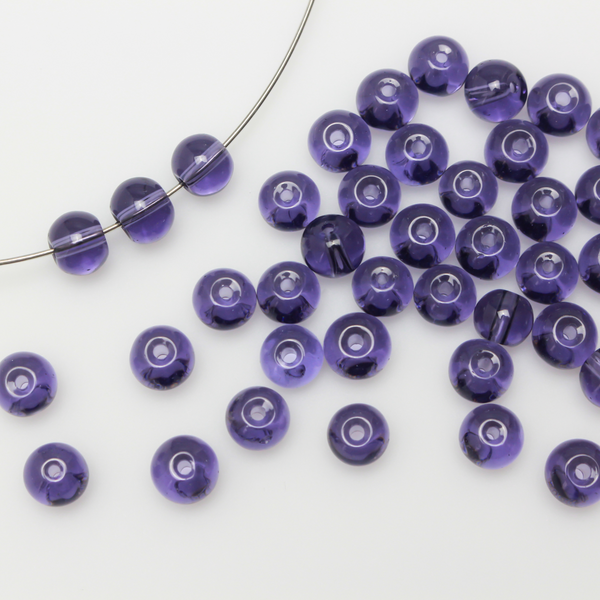 6mm round glass beads that are a transparent purple color.