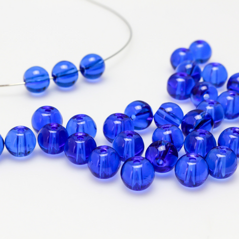 8mm round glass beads in a royal blue color that is transparent.