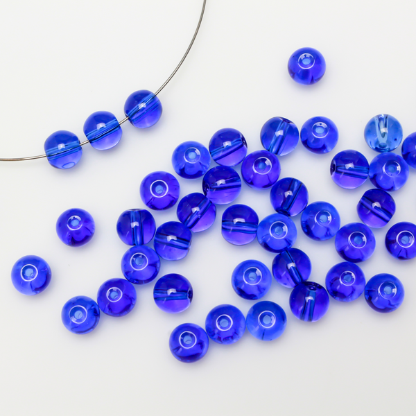 8mm round glass beads in a royal blue color that is transparent.