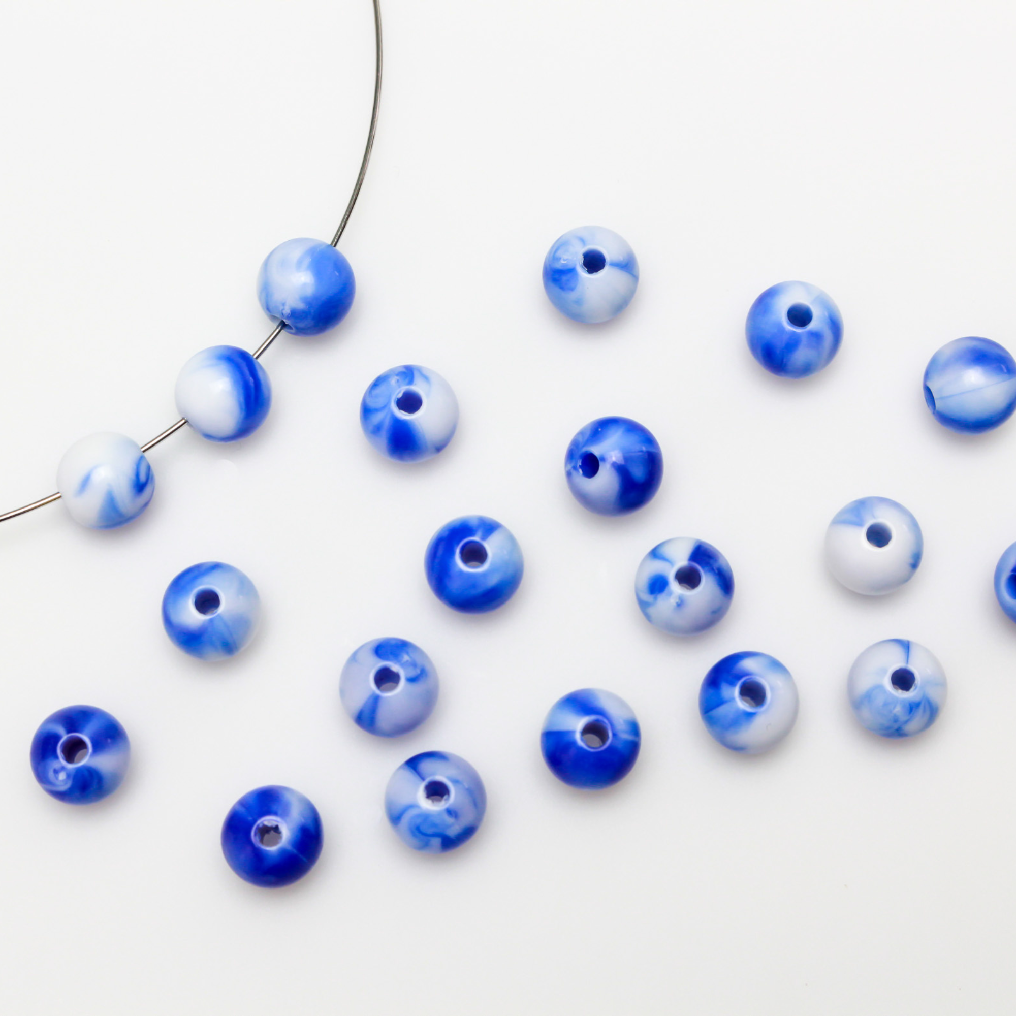 Round blue and white marbled opaque beads that are 8mm in diameter with a 1.5mm hole size