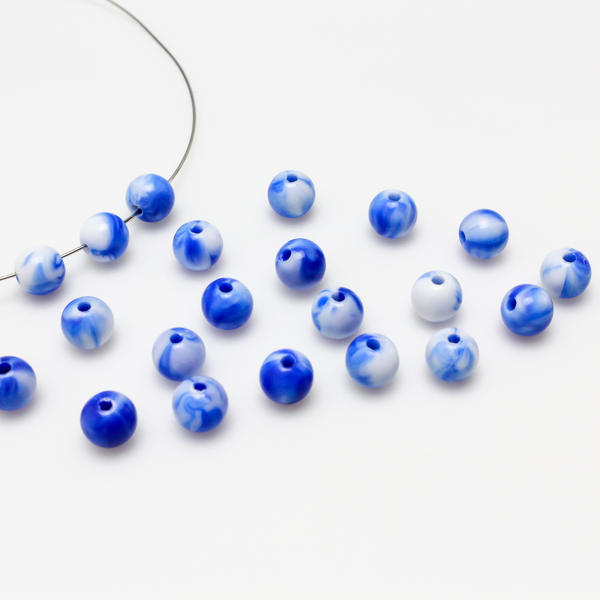 Round blue and white marbled opaque beads that are 8mm in diameter with a 1.5mm hole size