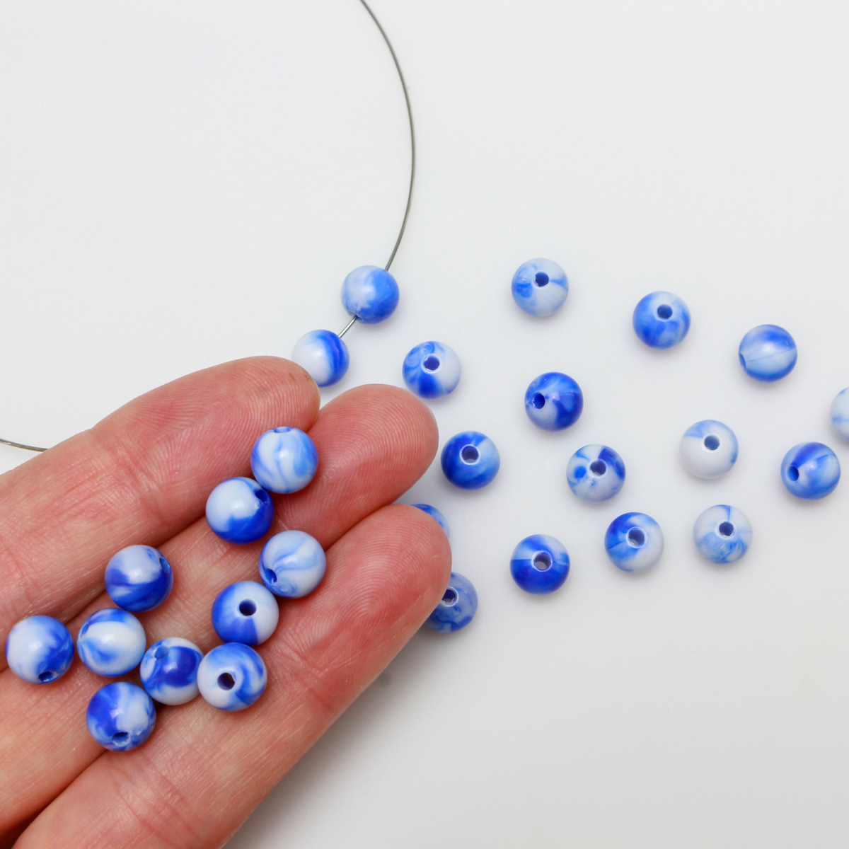 Round blue and white marbled opaque beads that are 8mm in diameter with a 1.5mm hole size