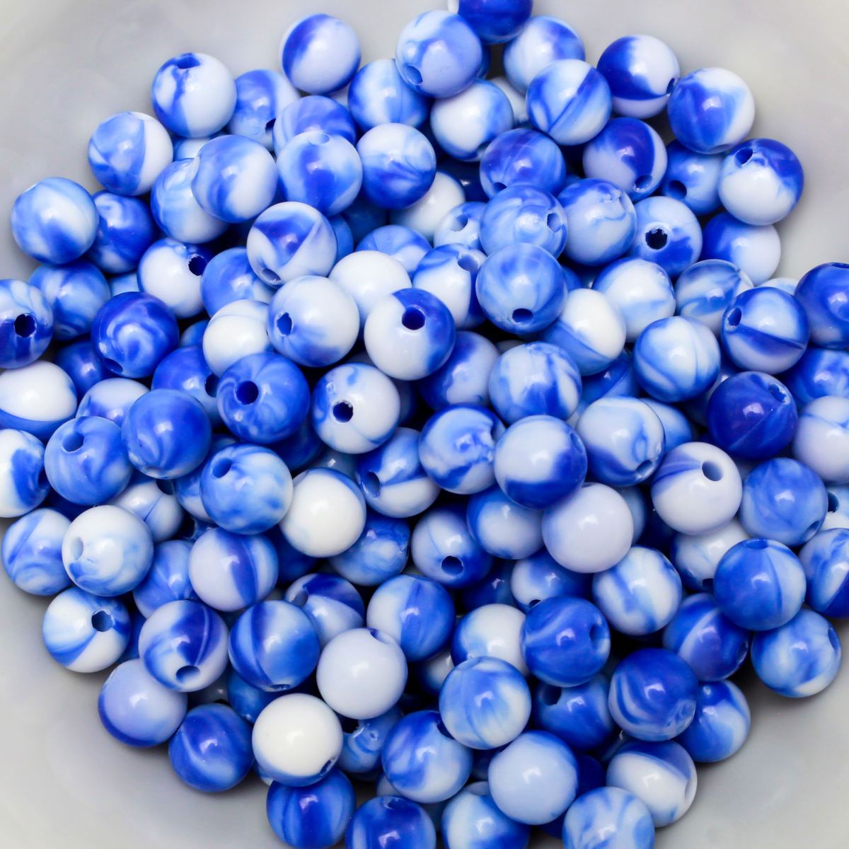 Round blue and white marbled opaque beads that are 8mm in diameter with a 1.5mm hole size