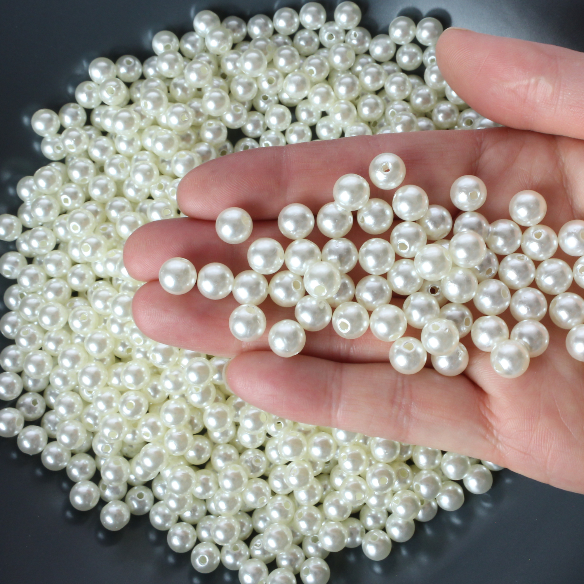 Plastic imitation pearl beads that are 8mm round with a 2mm hole size.