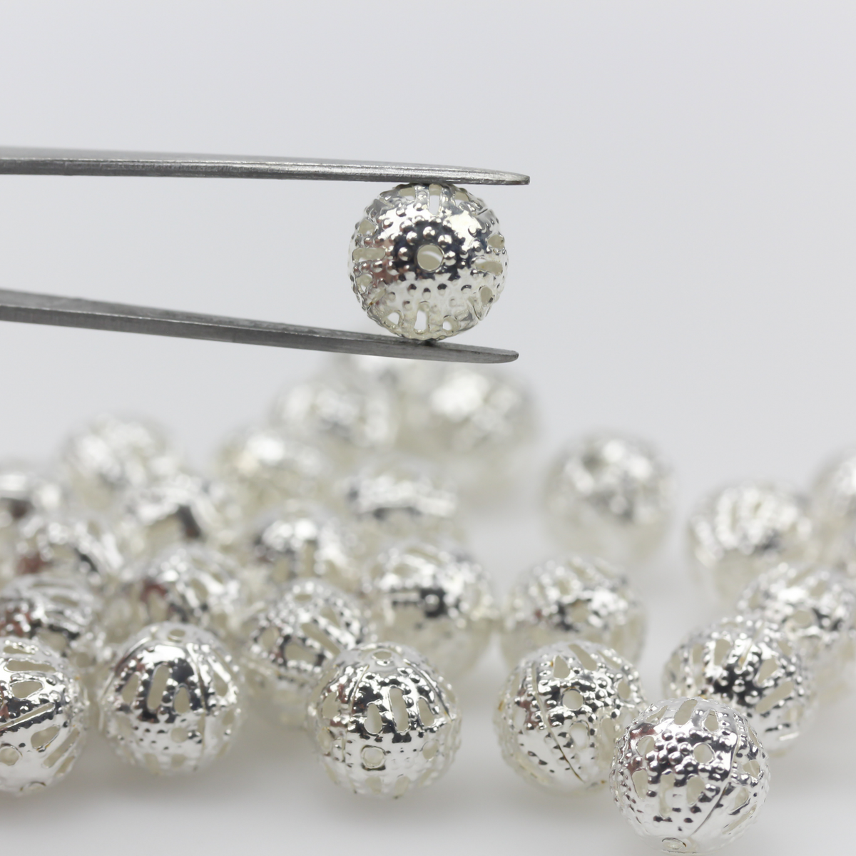 6mm lightweight metal beads that are hollow with a cutout (filigree) design and a shiny platinum silver color