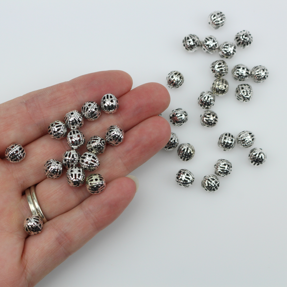 8mm round lightweight metal beads that are hollow with a cutout (filigree) design and an antiqued silver color