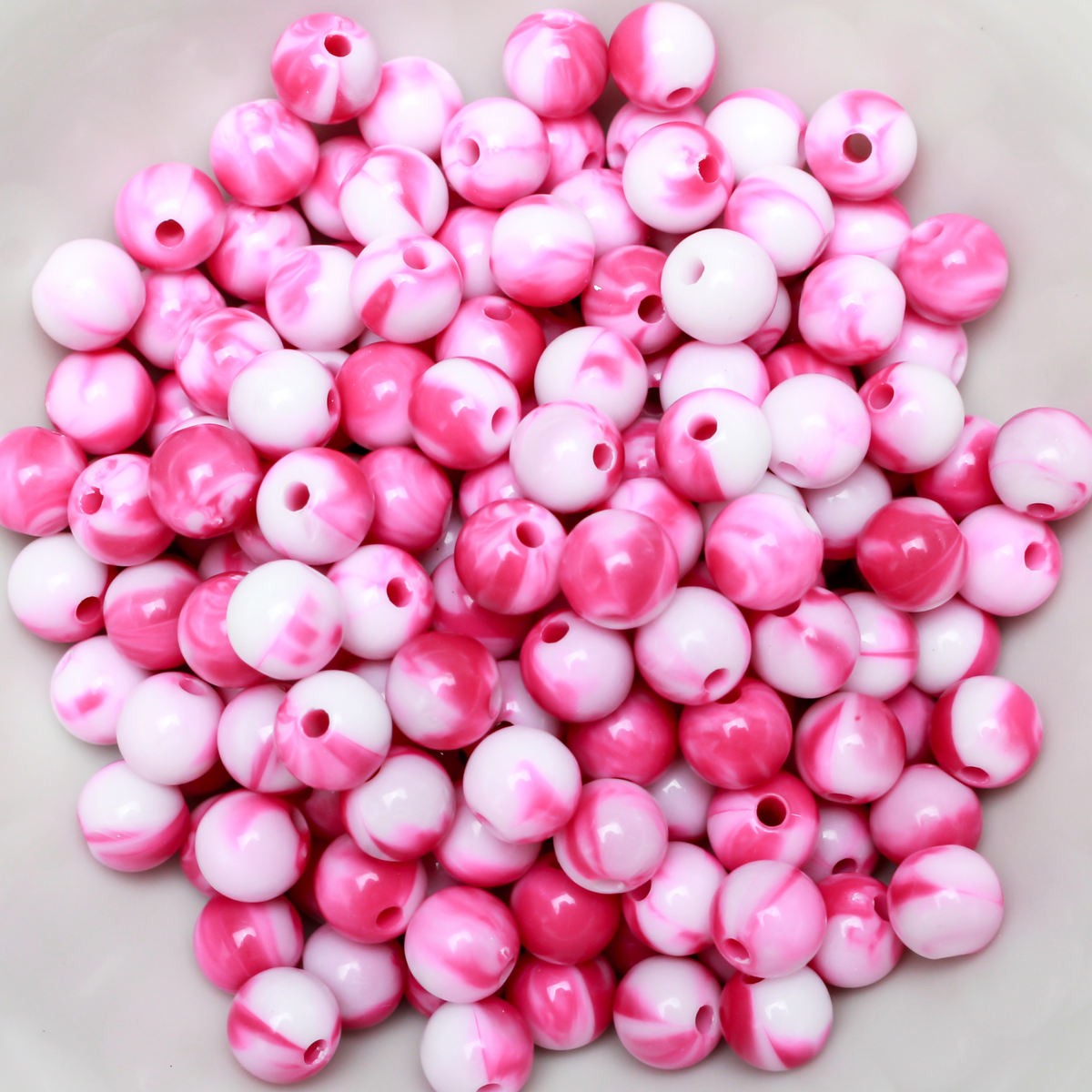 Round pink and white marbled opaque beads that are 8mm in diameter with a 1.5mm hole size