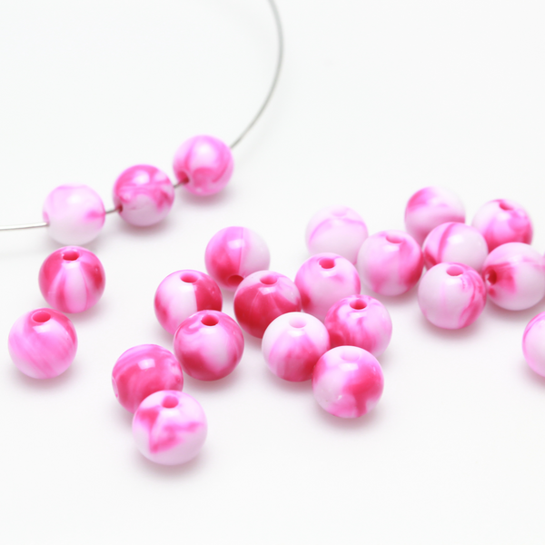 Round pink and white marbled opaque beads that are 8mm in diameter with a 1.5mm hole size
