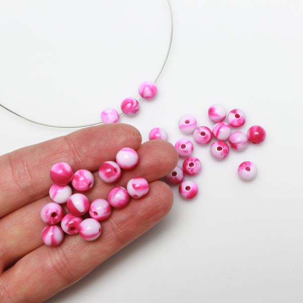 Round pink and white marbled opaque beads that are 8mm in diameter with a 1.5mm hole size