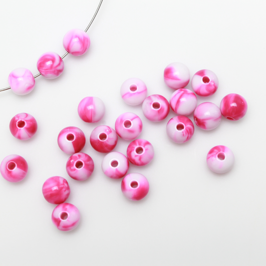 Round pink and white marbled opaque beads that are 8mm in diameter with a 1.5mm hole size