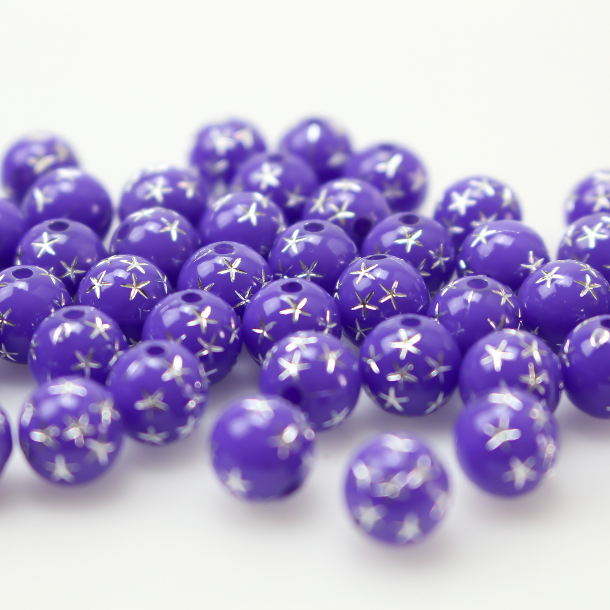 8mm round purple opaque beads that have a silver star design etched into them. 