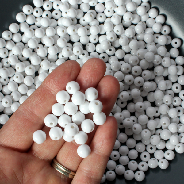 Round white opaque beads that are 8mm in diameter with a 1.5mm hole size.