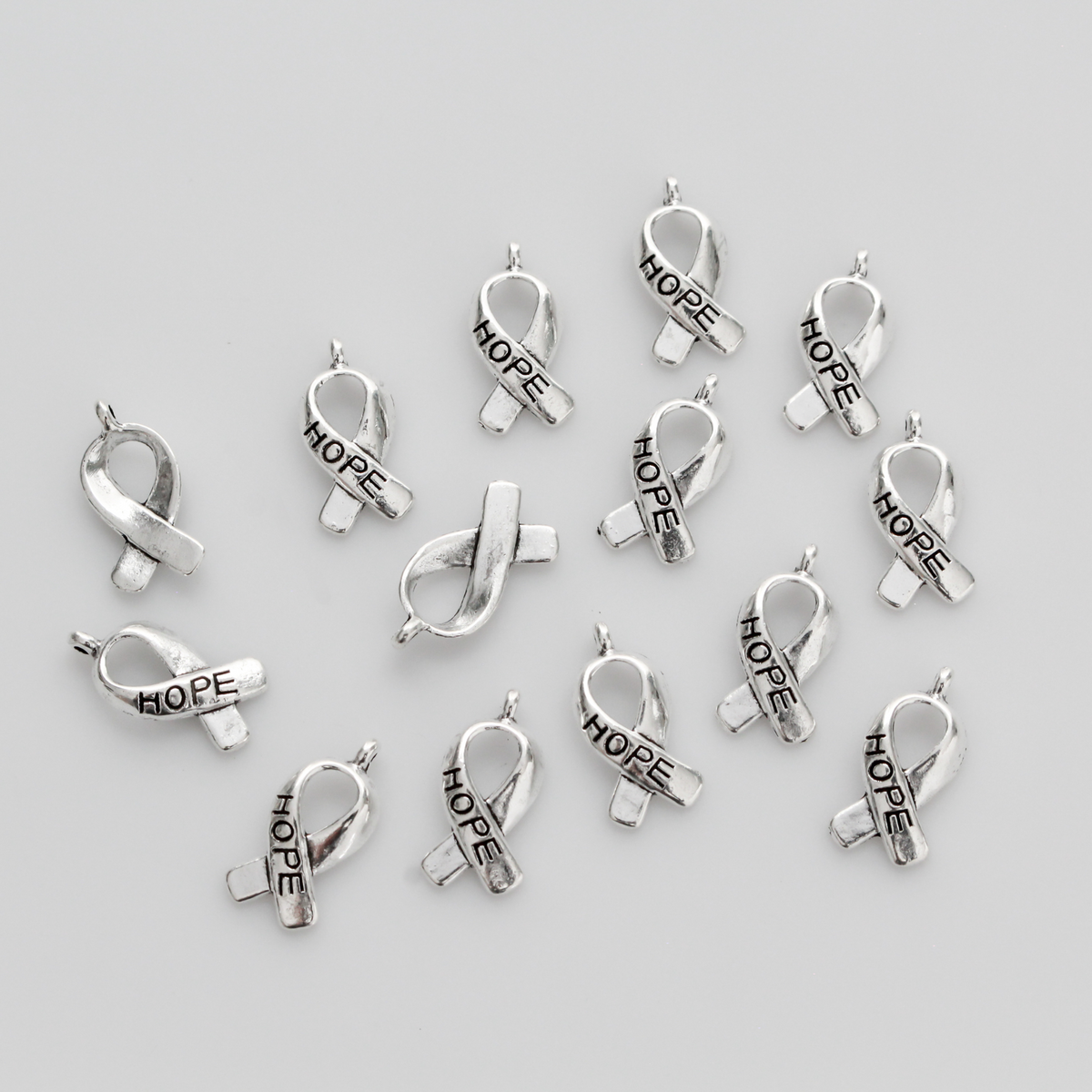 Silver awareness ribbon charms with the word "HOPE" engraved on the ribbon, 18mm long