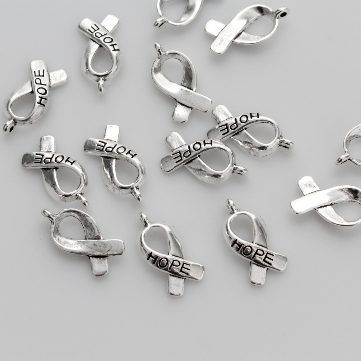 Silver awareness ribbon charms with the word "HOPE" engraved on the ribbon, 18mm long