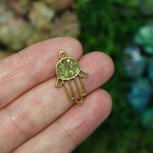 Gold tone Hamsa hand charm with an open design on the fingers, 22mm long by 15mm wide