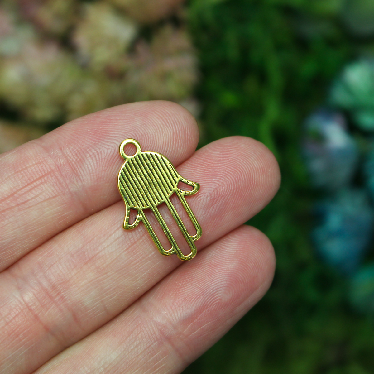 Gold tone Hamsa hand charm with an open design on the fingers, 22mm long by 15mm wide