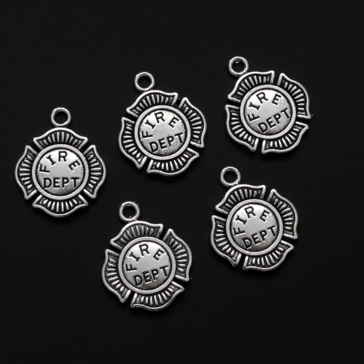 Small silver tone charms in the shape of the Maltese Cross and marked "FIRE DEPT" on the front.