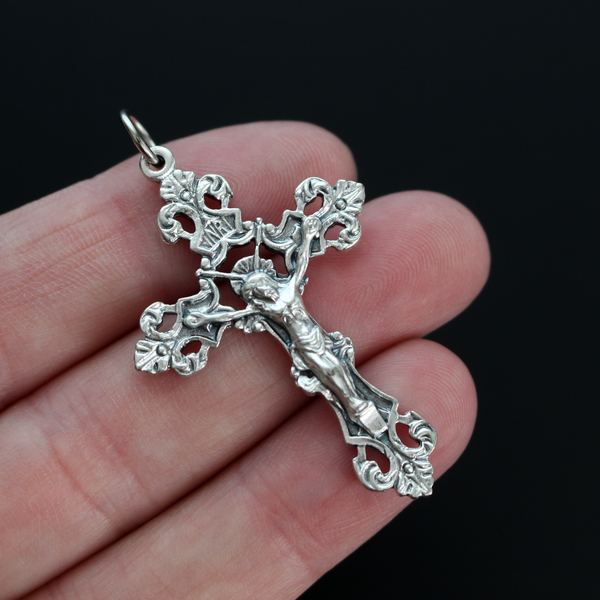 Ornate fleur de lis crucifix cross in an antiqued silver-tone color and filigree cut out design.