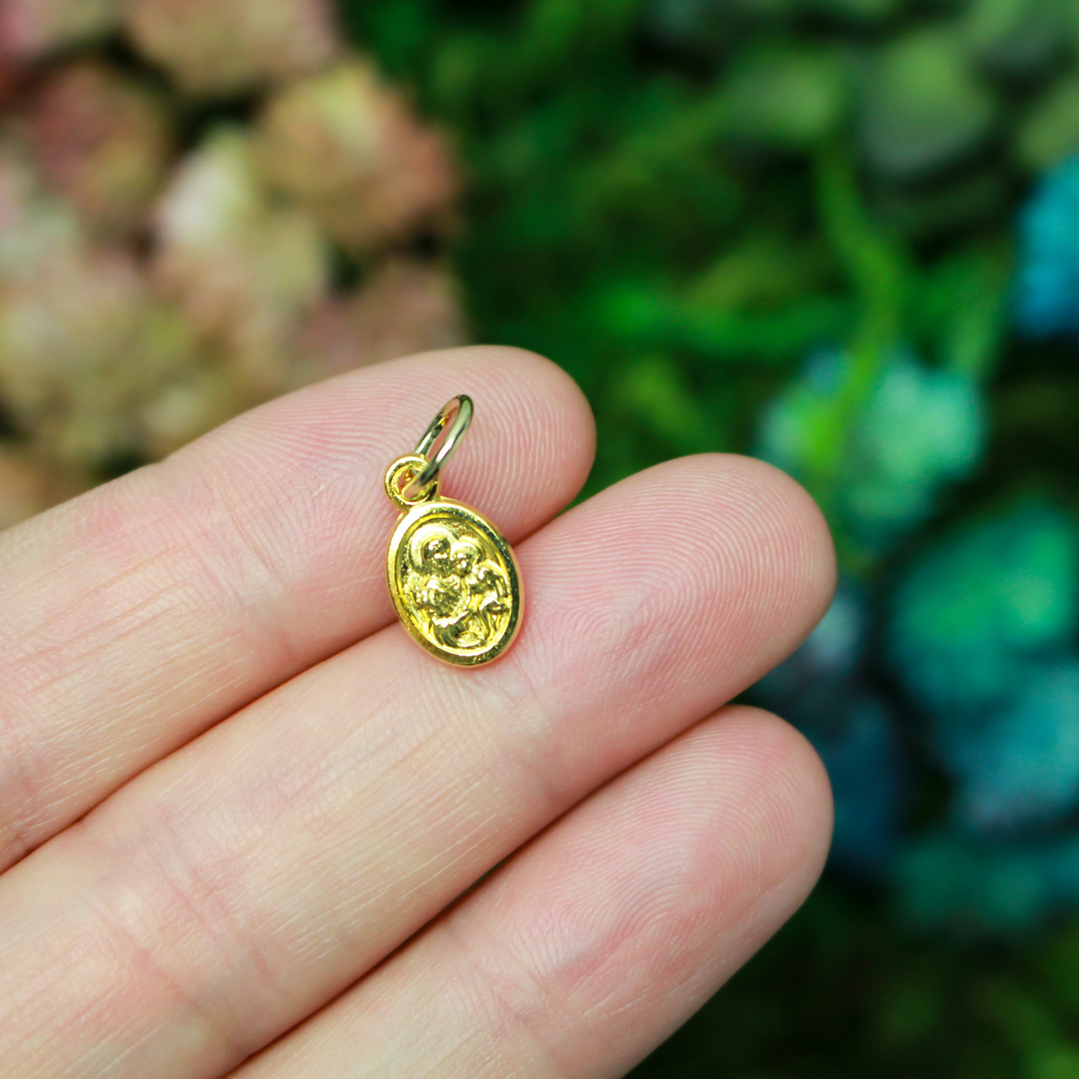Gold tone mini medal that depicts Saint Joseph holding the child Jesus on one side and the Holy Family depicted on the other side, 1/2" long