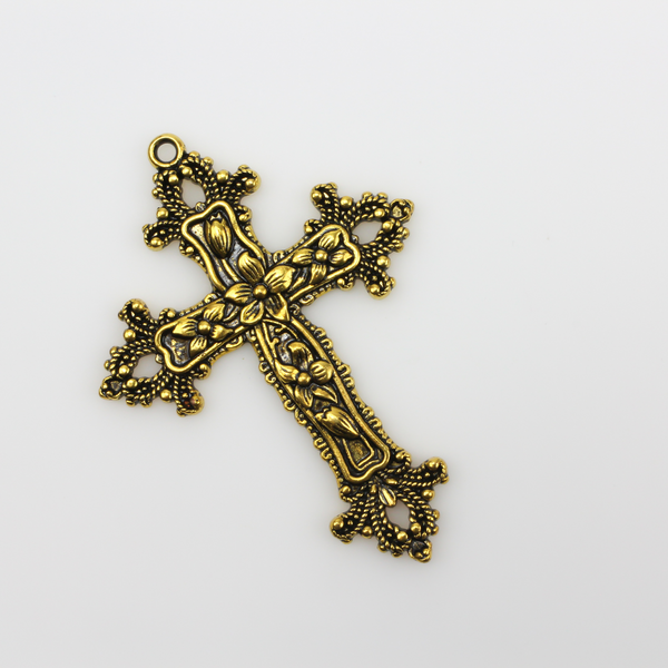 Large ornate cross pendant that has lilies on the crossbars and ornate fleur de lis ends with an antiqued golden color