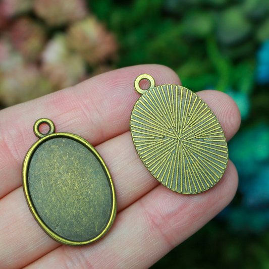 Flat oval pendant cabochon setting in an antiqued bronze tone color. This is a plain edge bezel cup with a 25mm x 18mm tray.