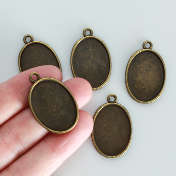 Flat oval pendant cabochon setting in an antiqued bronze tone color. This is a plain edge bezel cup with a 25mm x 18mm tray.