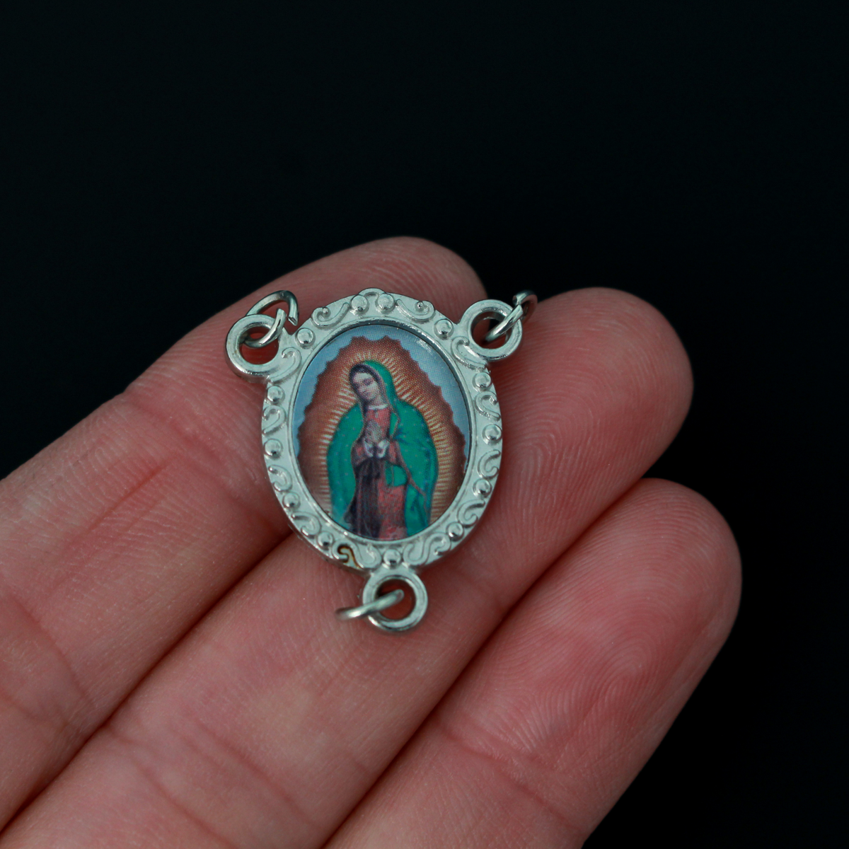 Rosary center that has a color image of Our Lady of Guadalupe inlaid in a silver oxidized center with a scroll detail on the edge