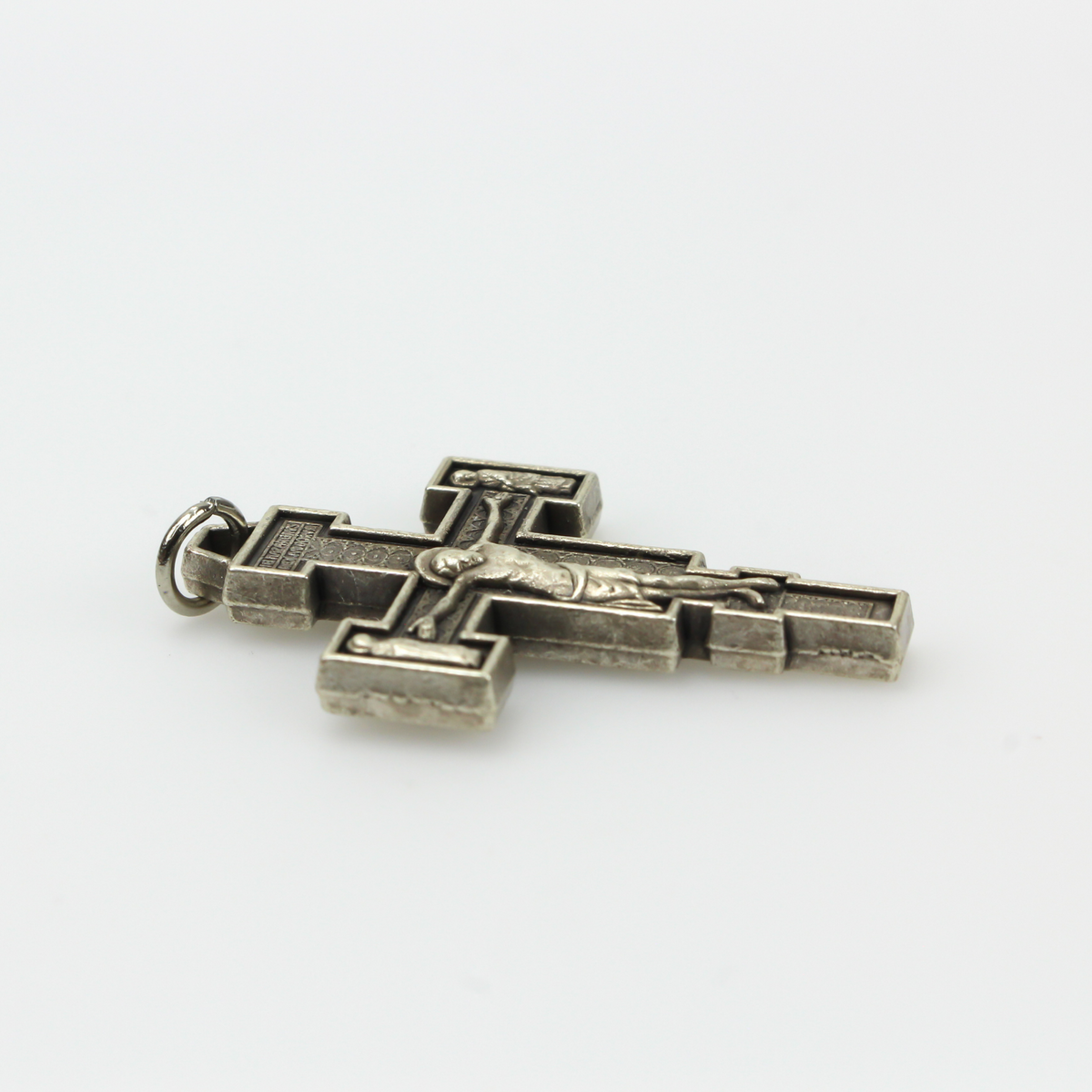 Extreme Humility Crucifix pendant. The backside has a pebbled texture and is marked "Italy" near the bottom.