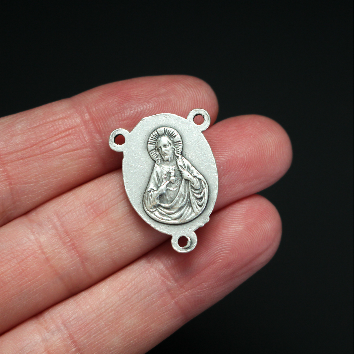 one inch long silver tone rosary centerpiece with the Blessed Virgin Mary on the front and the Sacred Heart of Jesus on the back