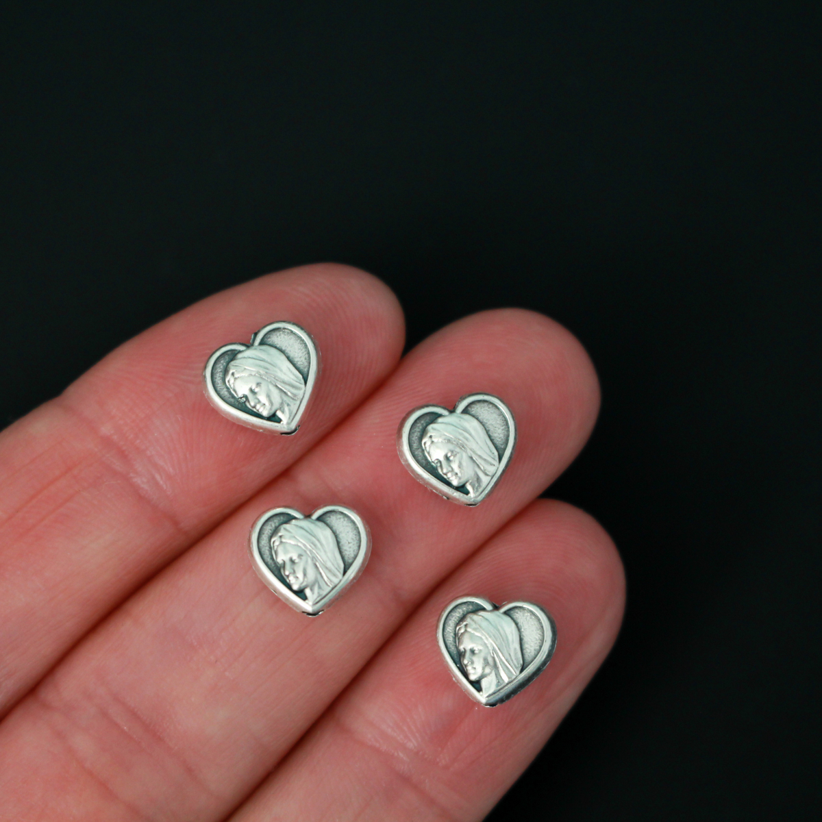 Heart shaped metal beads that features an image of Our Lady of Medjugorje on both sides.