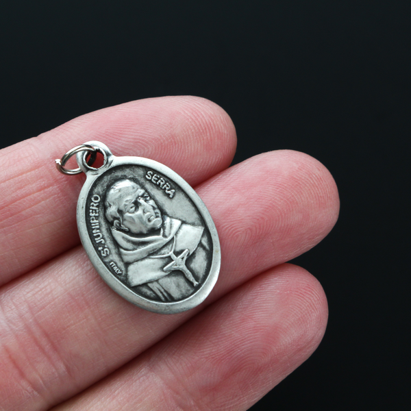 Saint Junípero Serra medal that depicts the saint on the front and "Pray For Us" on the back.