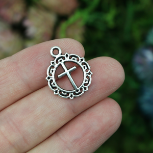 Round ornately framed cross charm in an antiqued silver-tone in color, 20mm long
