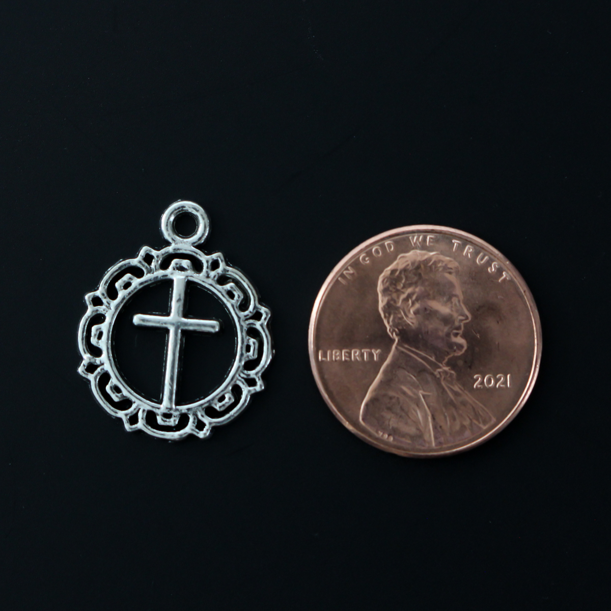 Round ornately framed cross charm in an antiqued silver-tone in color, 20mm long